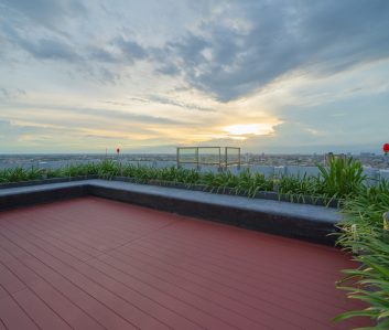 Sky garden on private rooftop of condominium or hotel, high rise architecture building with tree, grass field, and blue sky.